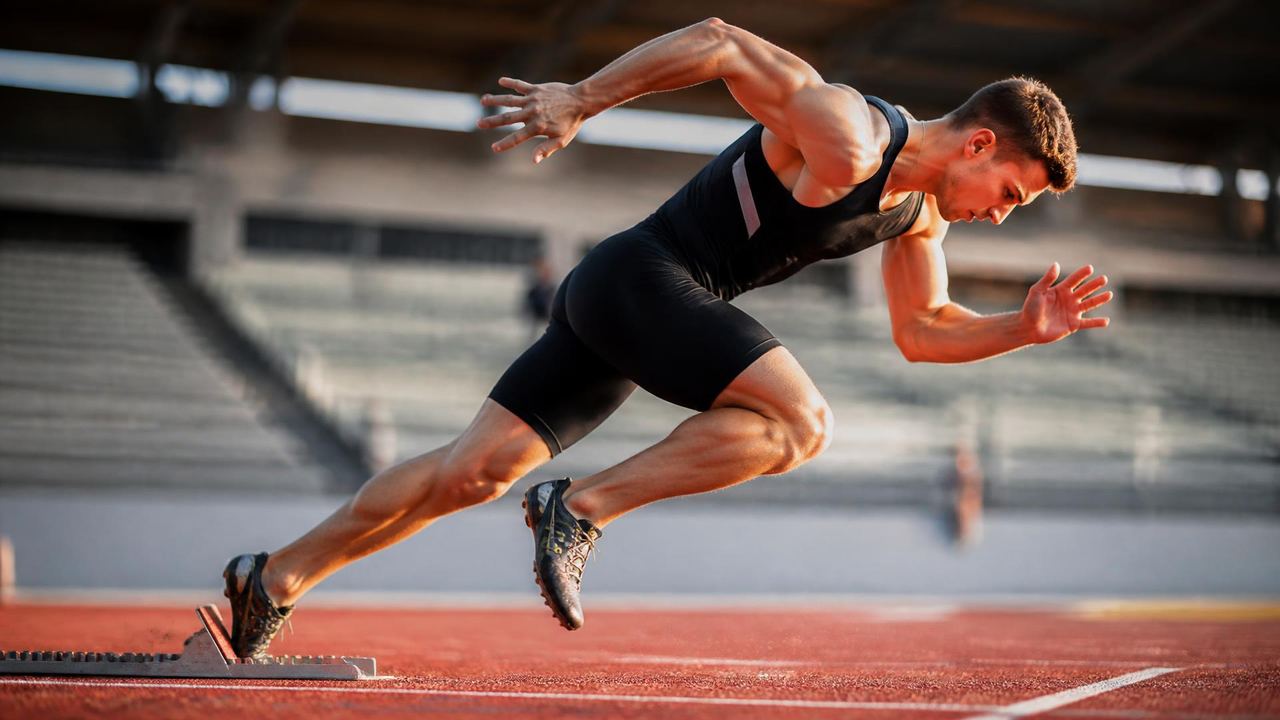 Sprinter exploding out of the starting blocks on a red synthetic track