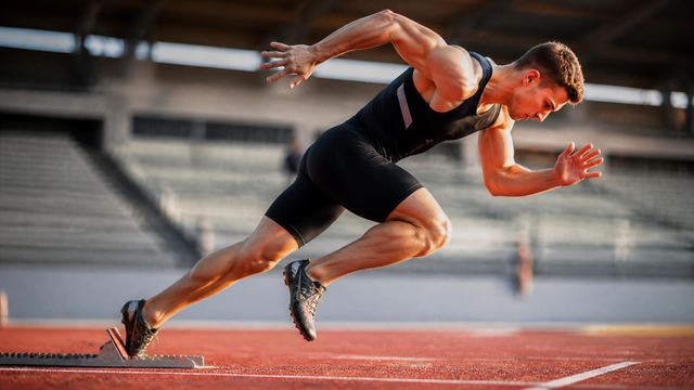 Sprinter driving out of the blocks, spikes loaded against the track